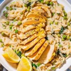 An overhead photo of a serving of lemon chicken orzo on a plate with lemon wedges.