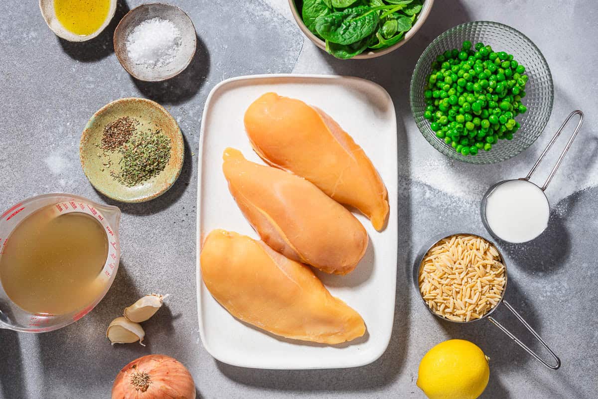 Ingredients for lemon chicken orzo chicken breasts, salt, black pepper, oregano, olive oil, onion, garlic, orzo, chicken broth, lemon, peas, milk, and baby spinach.