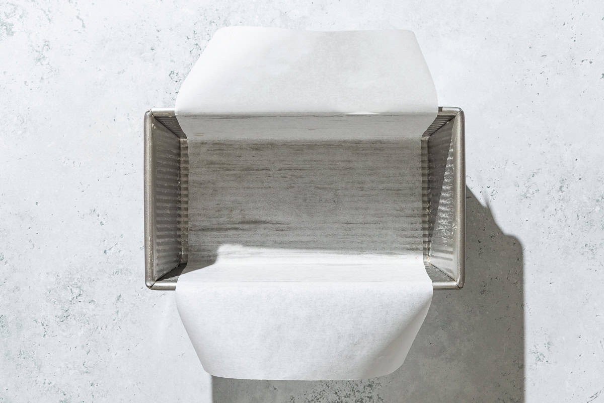 An overhead photo of a loaf pan lined with parchment paper.