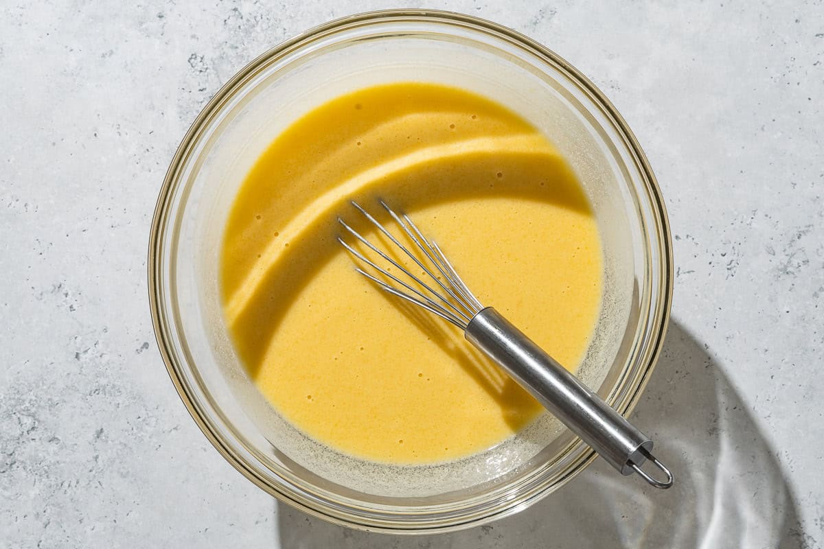 An overhead photo of the wet ingredients for the yogurt cake in a mixing bowl with a whisk.