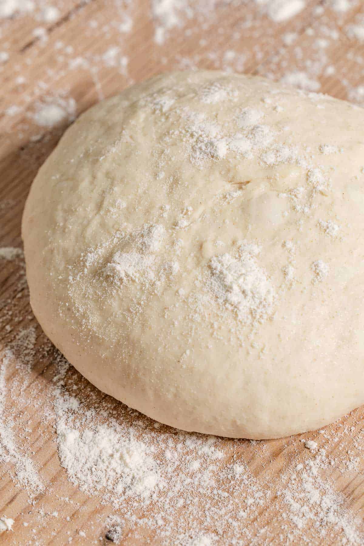 A close up of a ball of dough on a table dusted with flour.