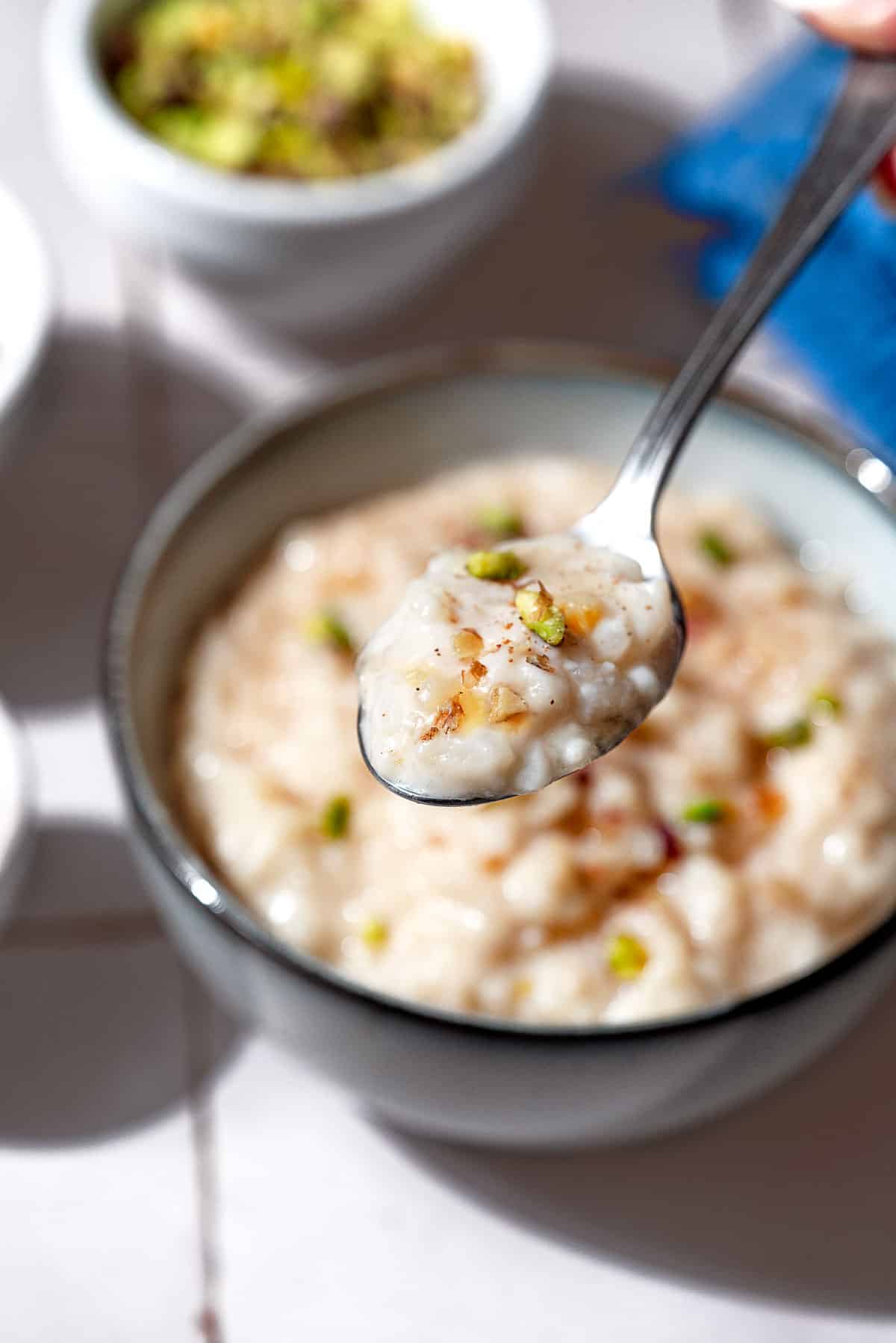 A close up of a spoonful of easy rice pudding being held over the bowl with the rest of the pudding.