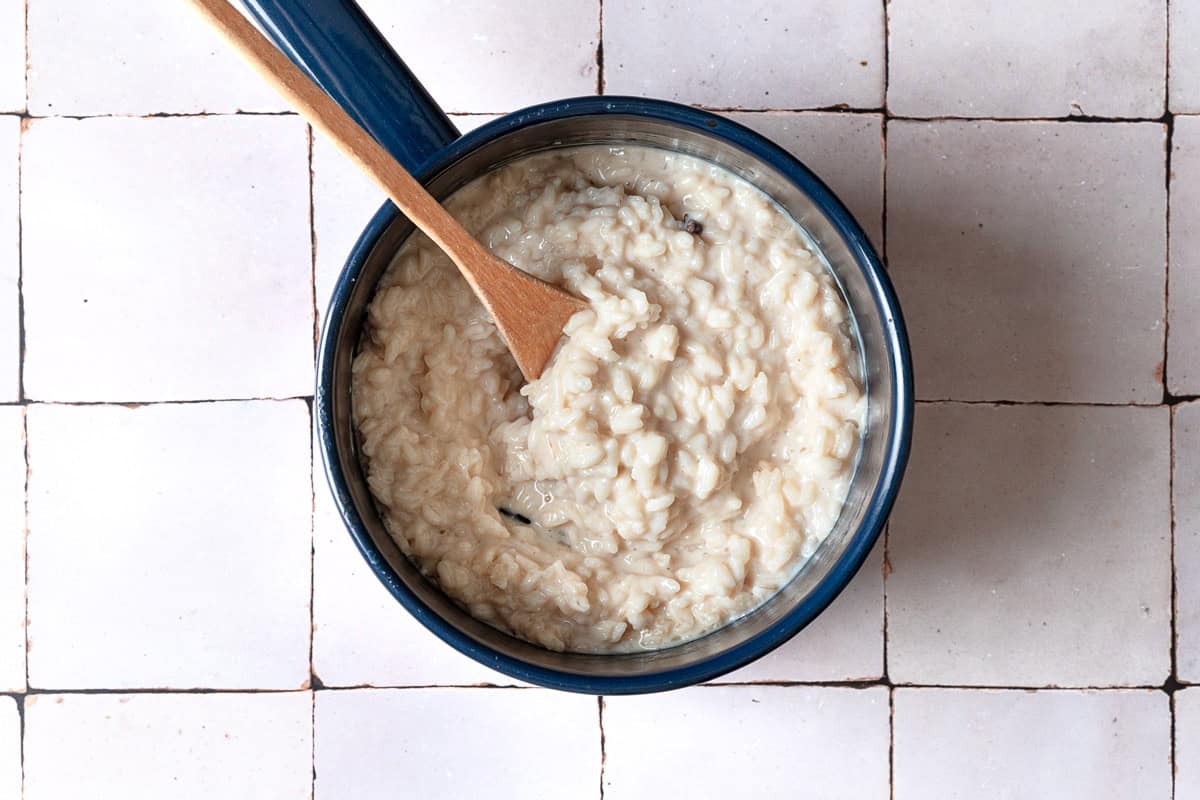 Easy rice pudding in a saucepan with a wooden spoon.