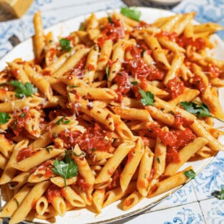 An overhead photo of arrabbiata sauce pasta on a serving platter with a spoon.