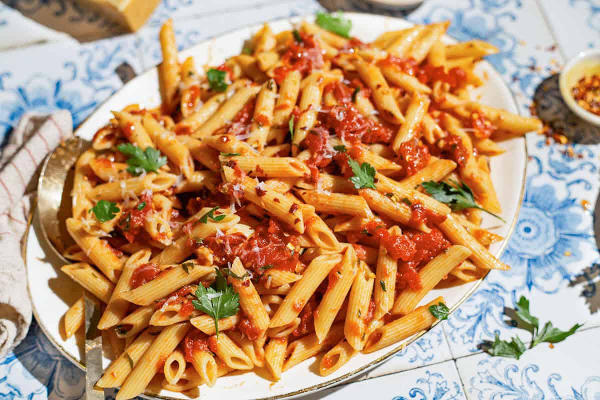 An overhead photo of arrabbiata sauce pasta on a serving platter with a spoon.