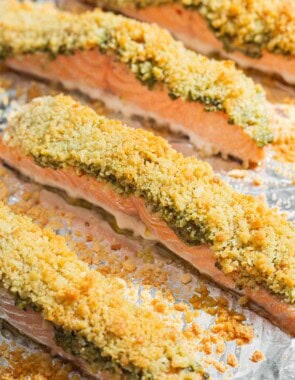 4 pesto salmon fillets on a baking sheet lined with aluminum foil.