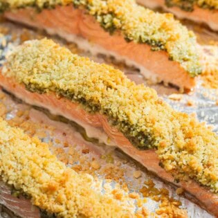 4 pesto salmon fillets on a baking sheet lined with aluminum foil.