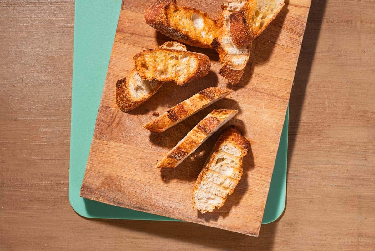 An overhead photo of several slices of the toasted baguette on a cutting board.