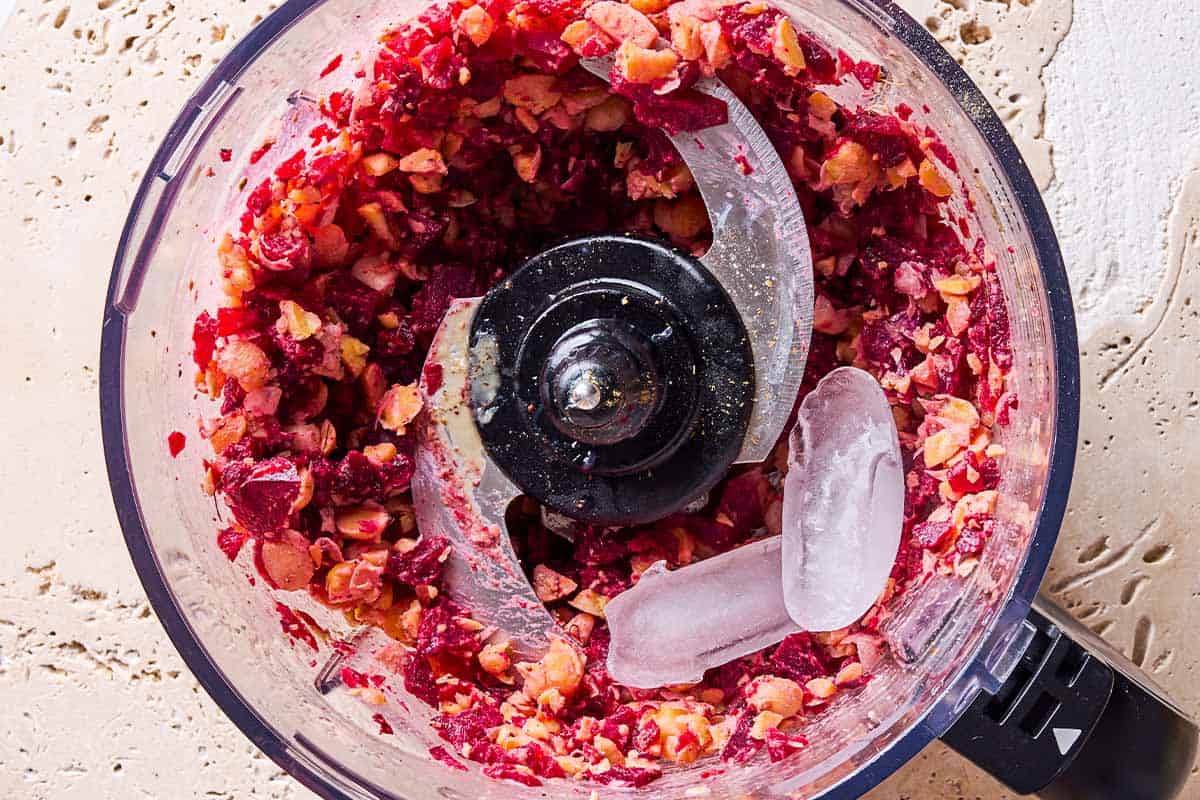 The ingredients for beet hummus just after being slightly mixed together in the bowl of a food processor fitted with a blade.