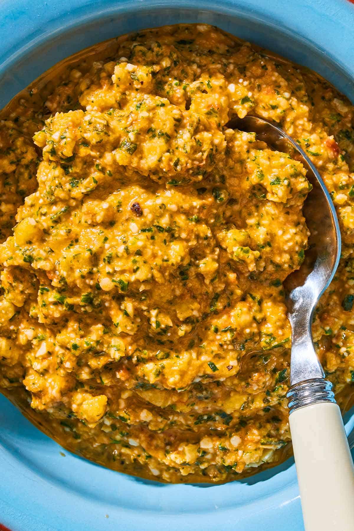 A close up of pesto alla trapanese in a bowl with a spoon.