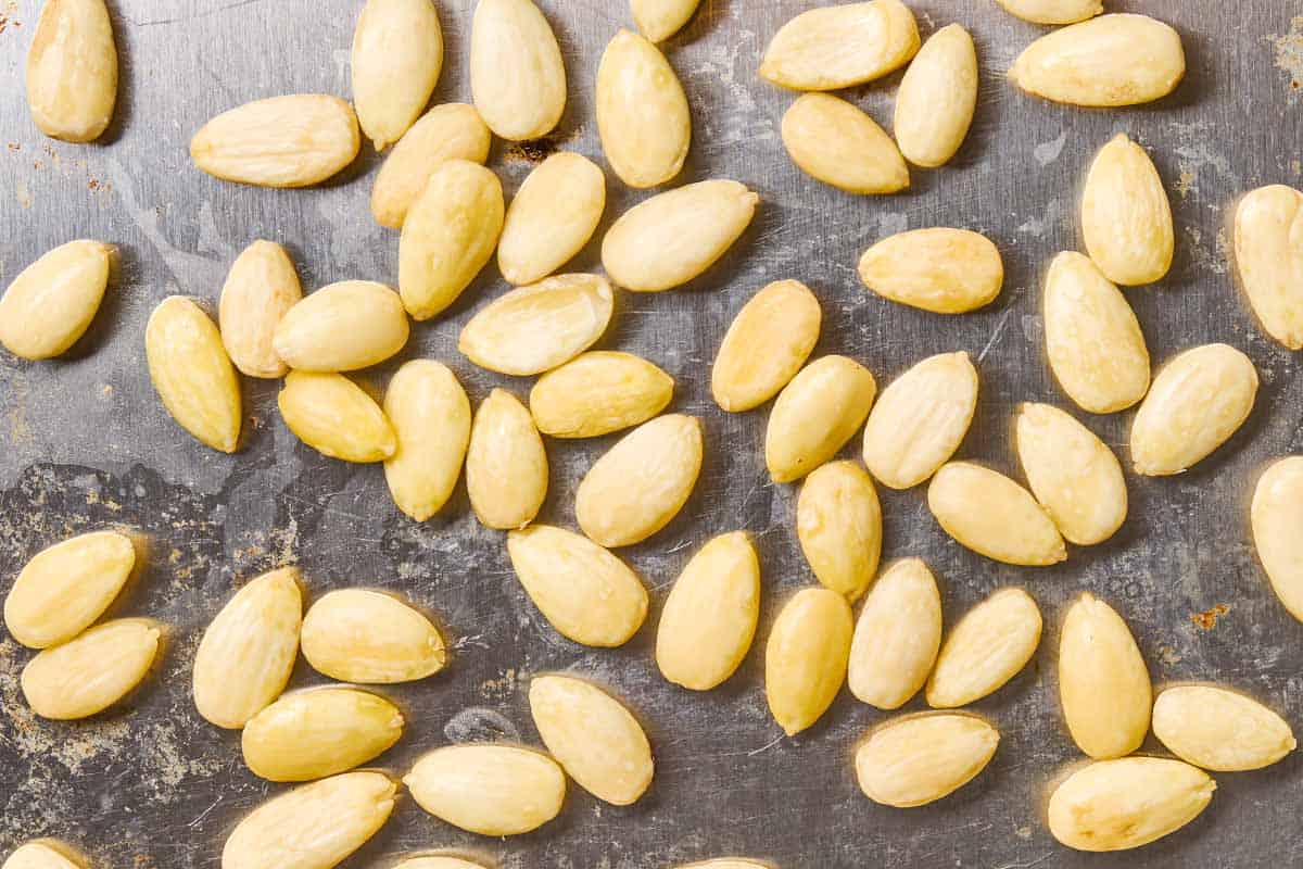 A close up of blanched almonds on a baking sheet.