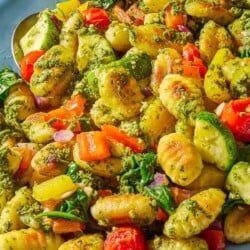 A close up of crispy gnocchi with pesto on a serving platter with a spoon.