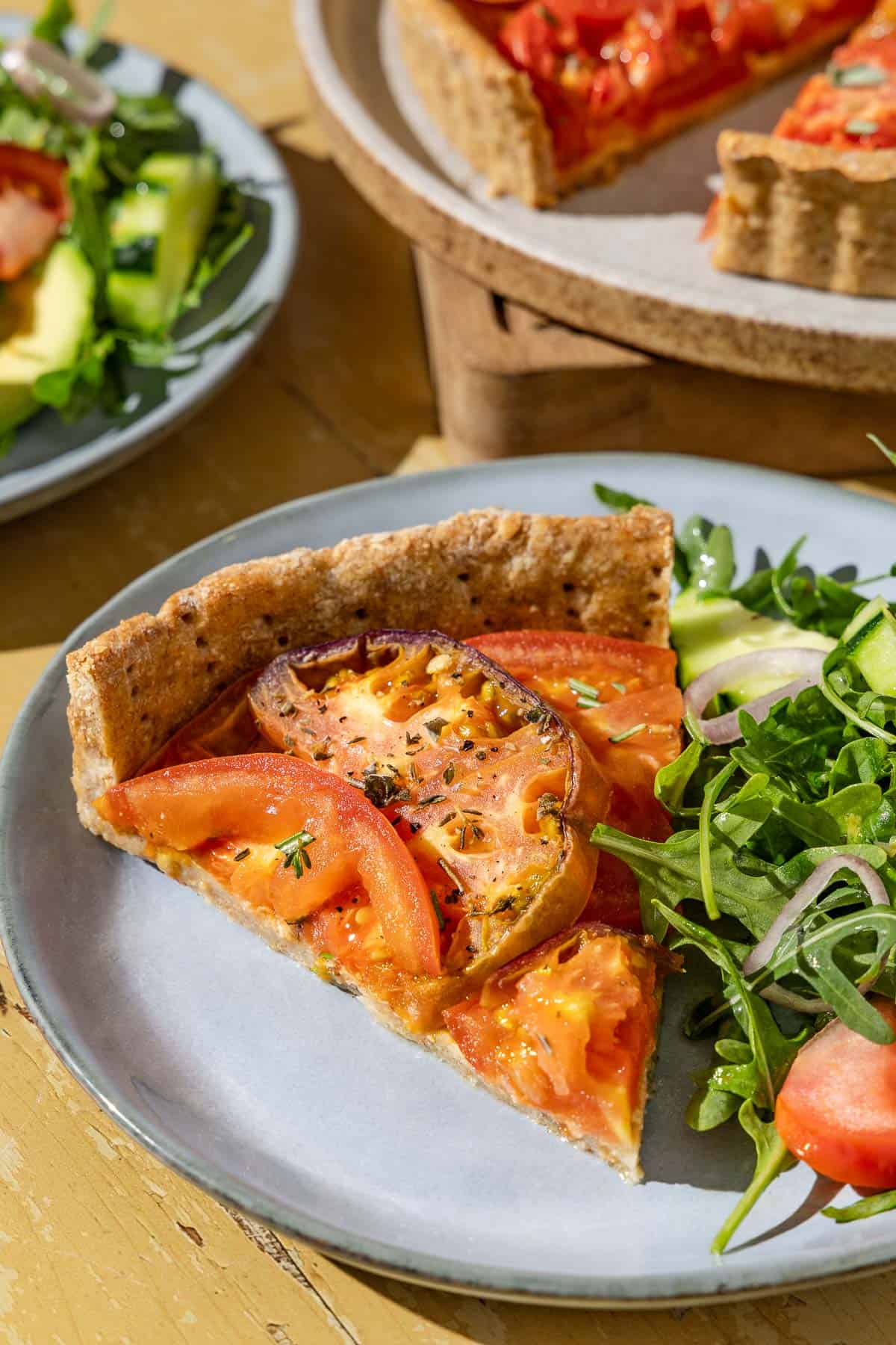 A close up of a slice of the tomato tart on a plate with a serving of salad.