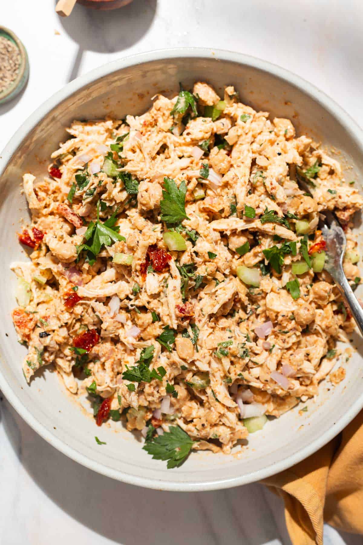 An overhead photo of the chickpea chicken salad in a serving bowl with a fork.