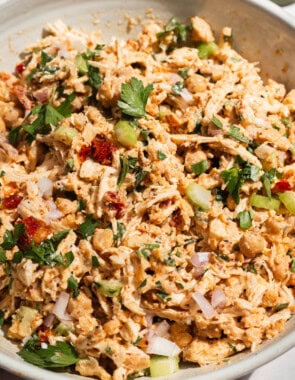 The chickpea chicken salad in a serving bowl with a fork. Next to this is a cloth napkin and a small bowl of salt.