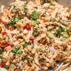 A close up of chickpea chicken salad in a serving bowl with a fork.