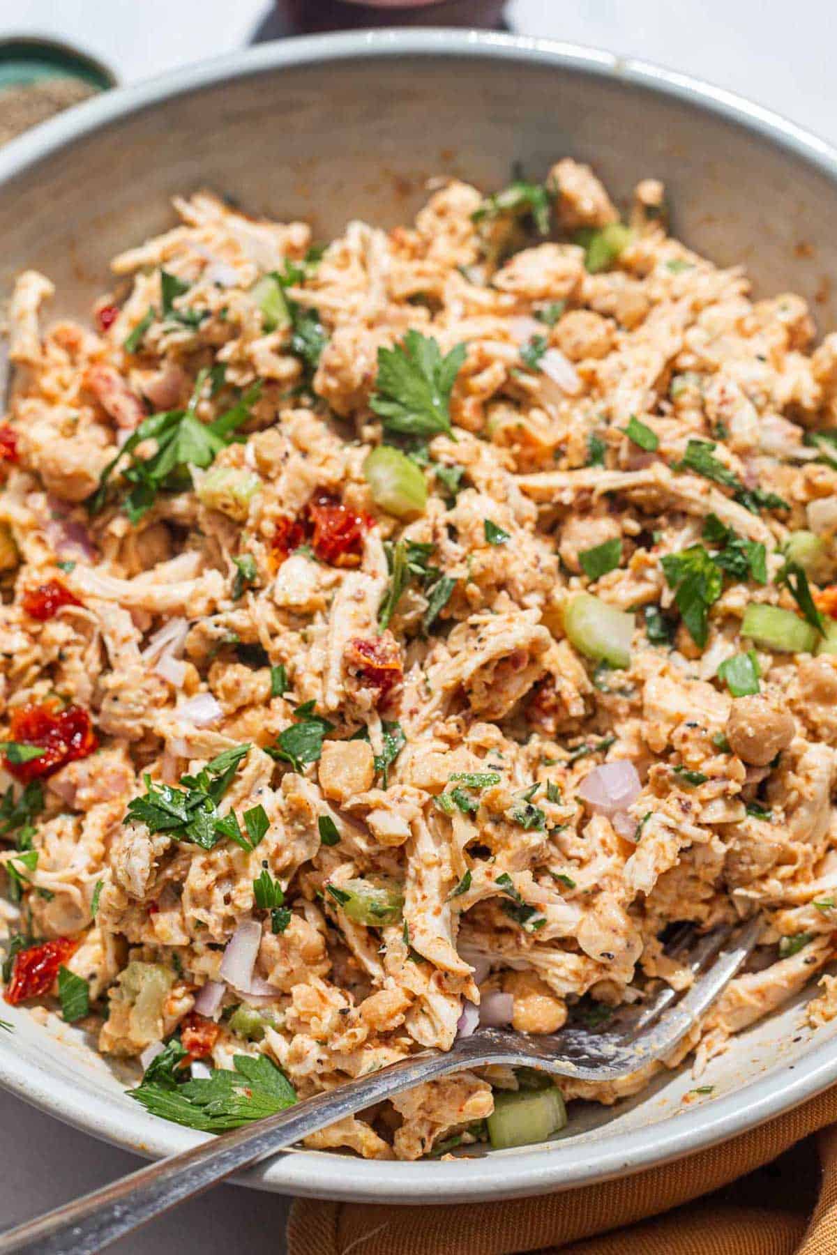 A close up of chickpea chicken salad in a serving bowl with a fork.