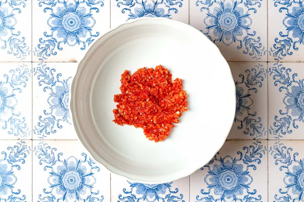 Chopped onion, red pepper paste, and tomato paste in a mixing bowl.