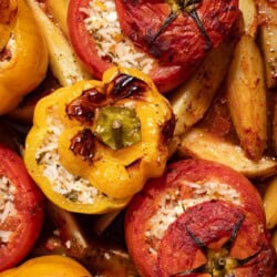 A close up of gemista greek stuffed vegetables with potato wedges.