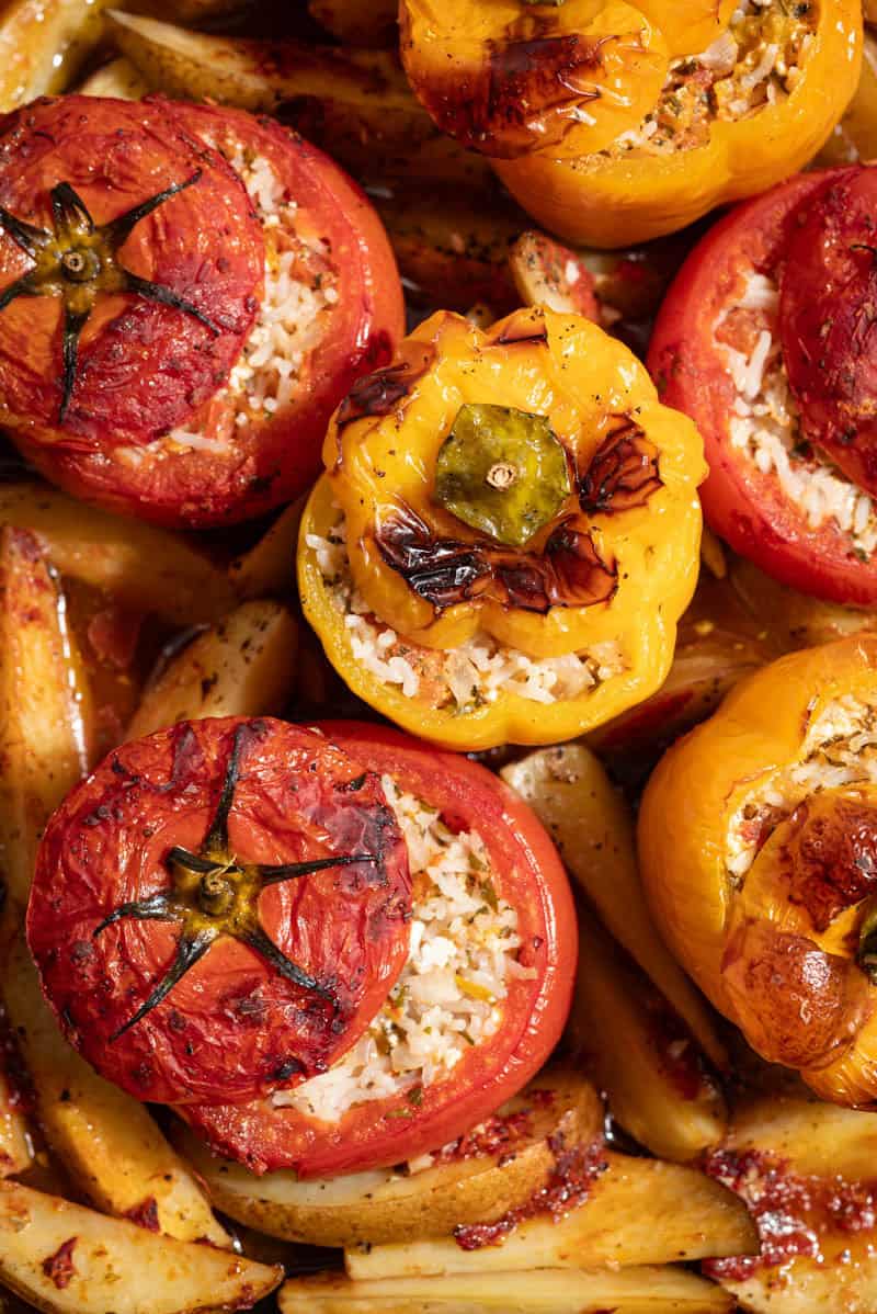 A close up photo of gemista greek stuffed vegetables with potato wedges.