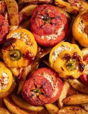 A close up of gemista greek stuffed vegetables with potato wedges.