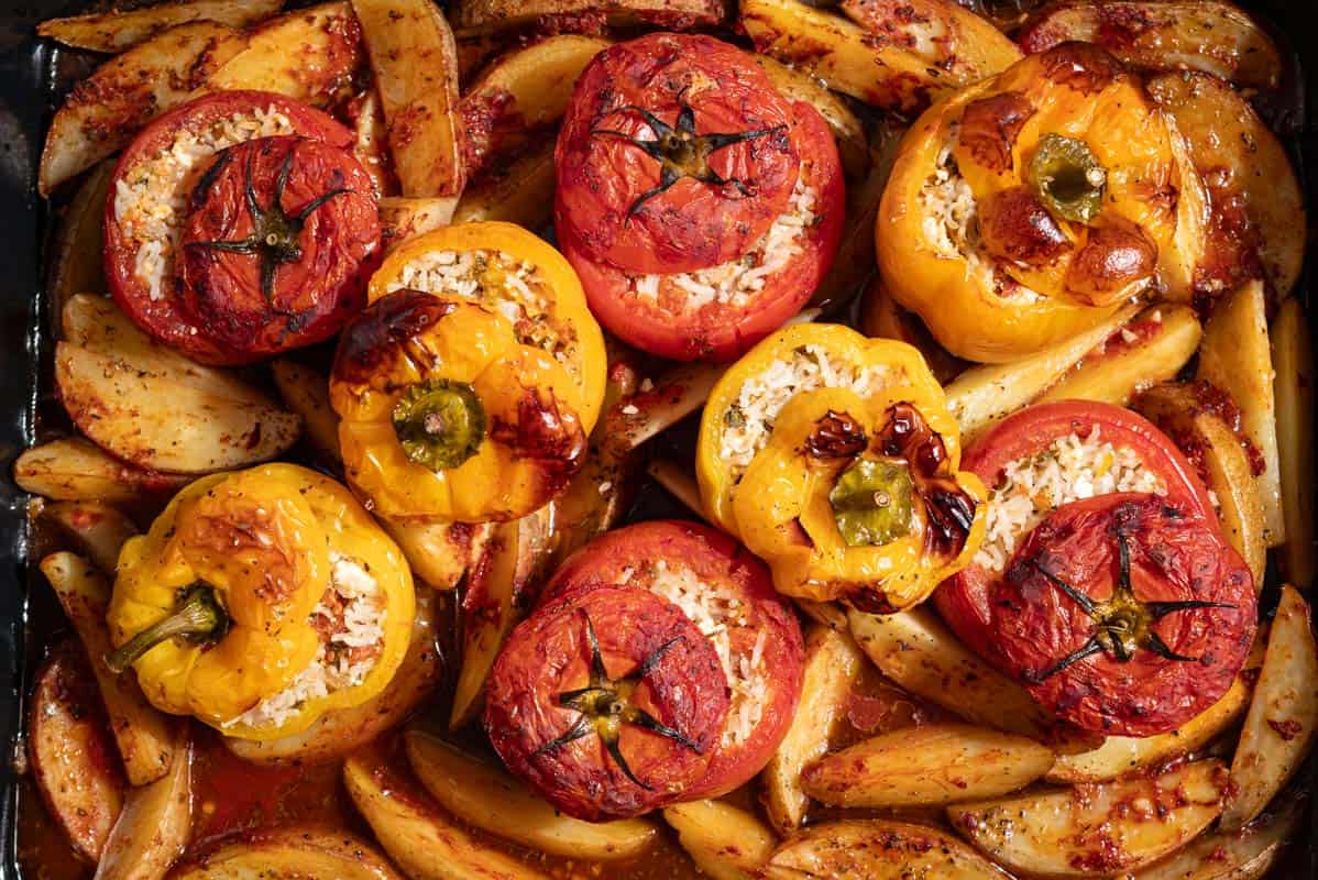 A close up of gemista greek stuffed vegetables with potato wedges.