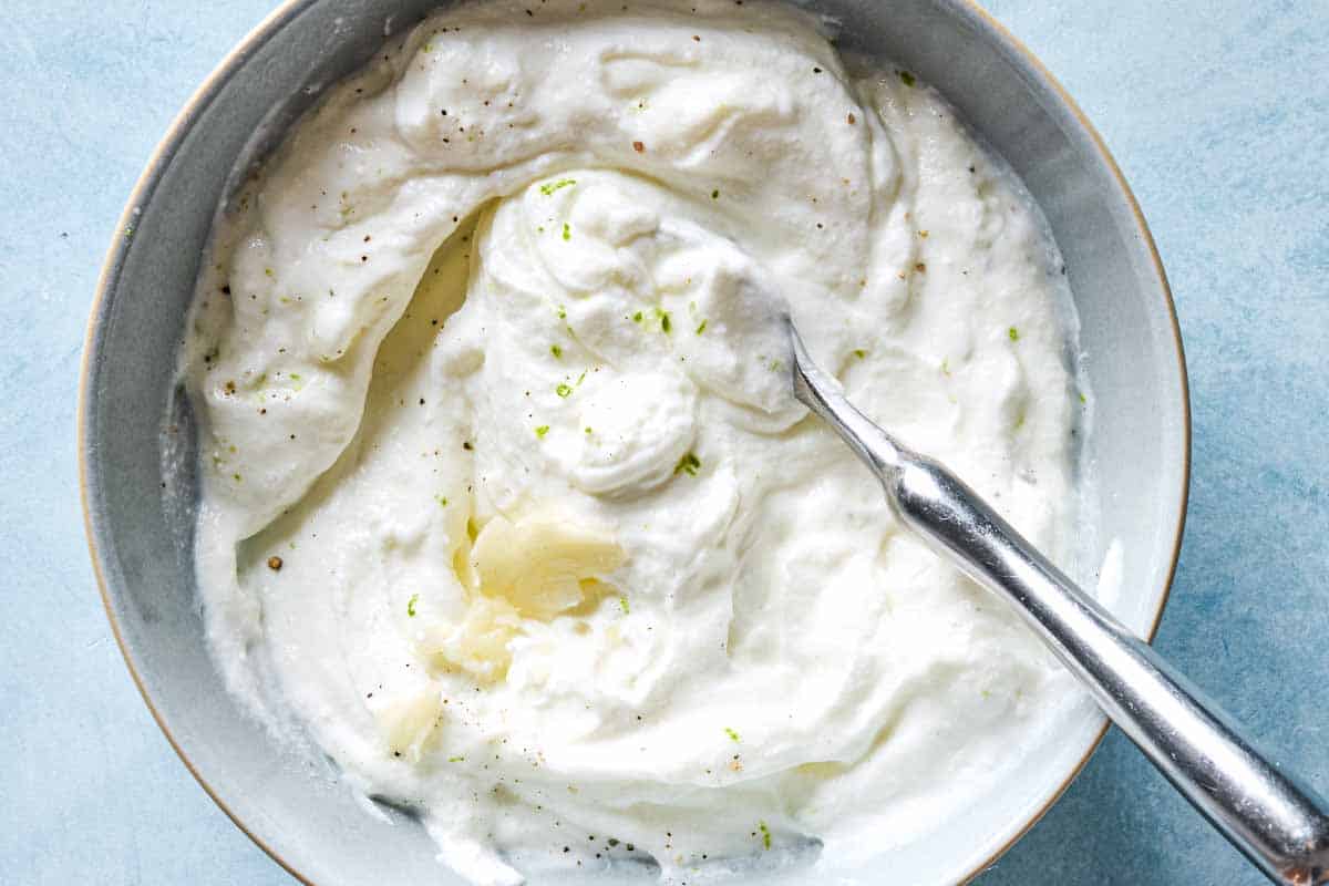 An overhead photo of the yogurt sauce for the borani kadoo in a bowl with a spoon.