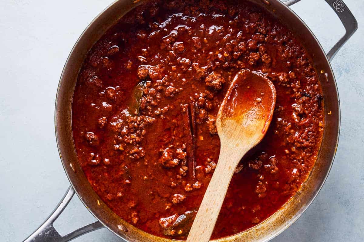 An overhead photo of the meat sauce for the Greek Shepherd's Pie in a skillet with a wooden spoon.