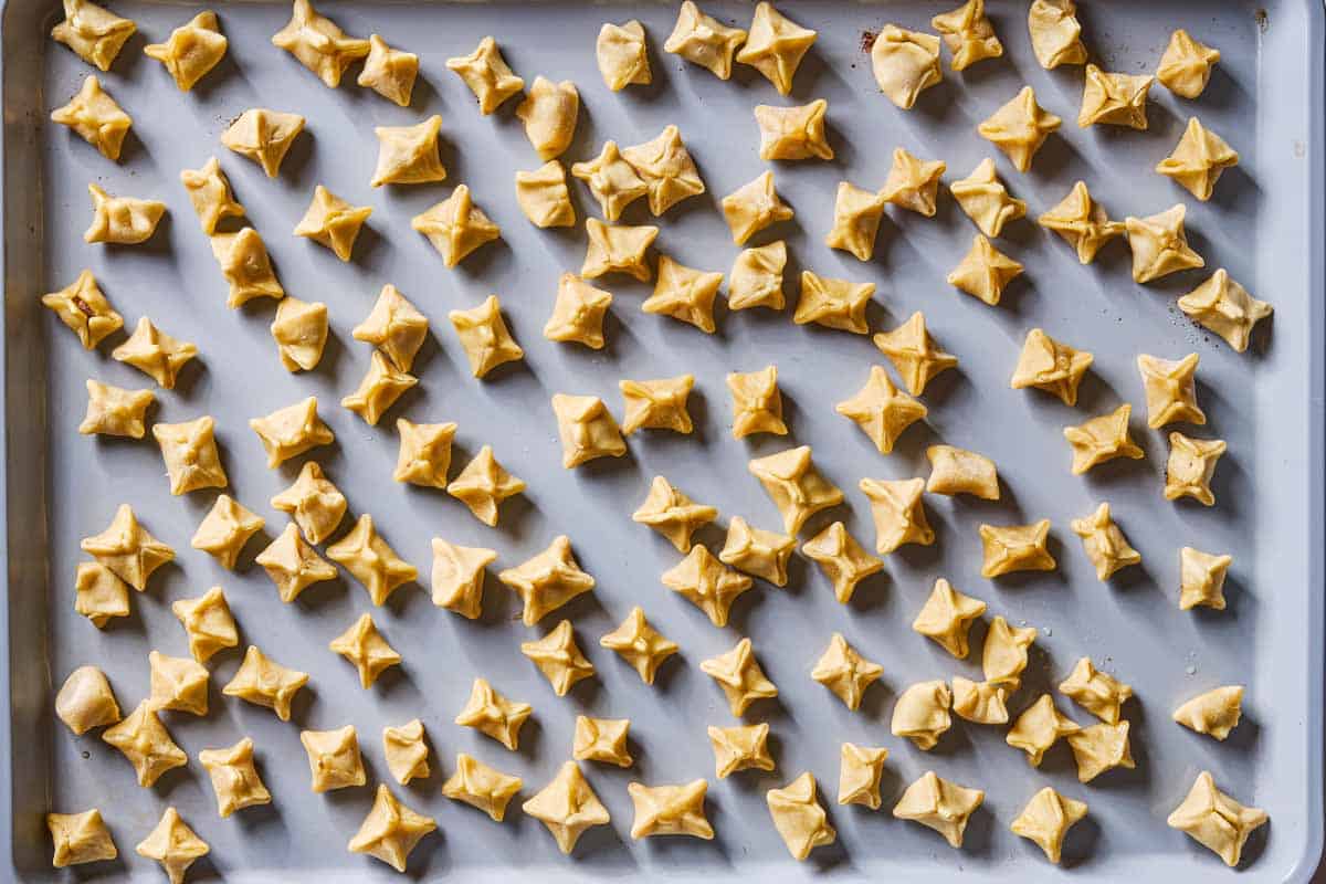 An overhead photo of unboiled sealed manti on a baking sheet.