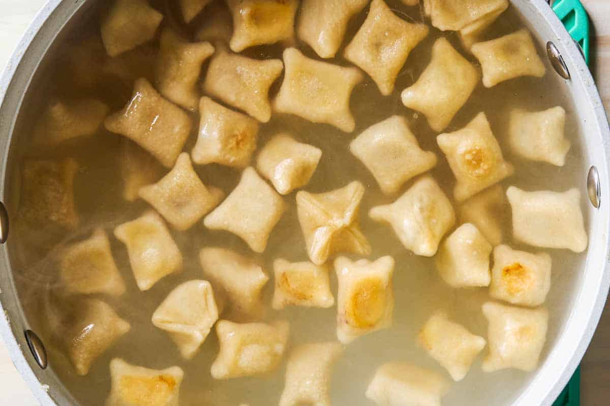 A close up of manti boiling in a pot.