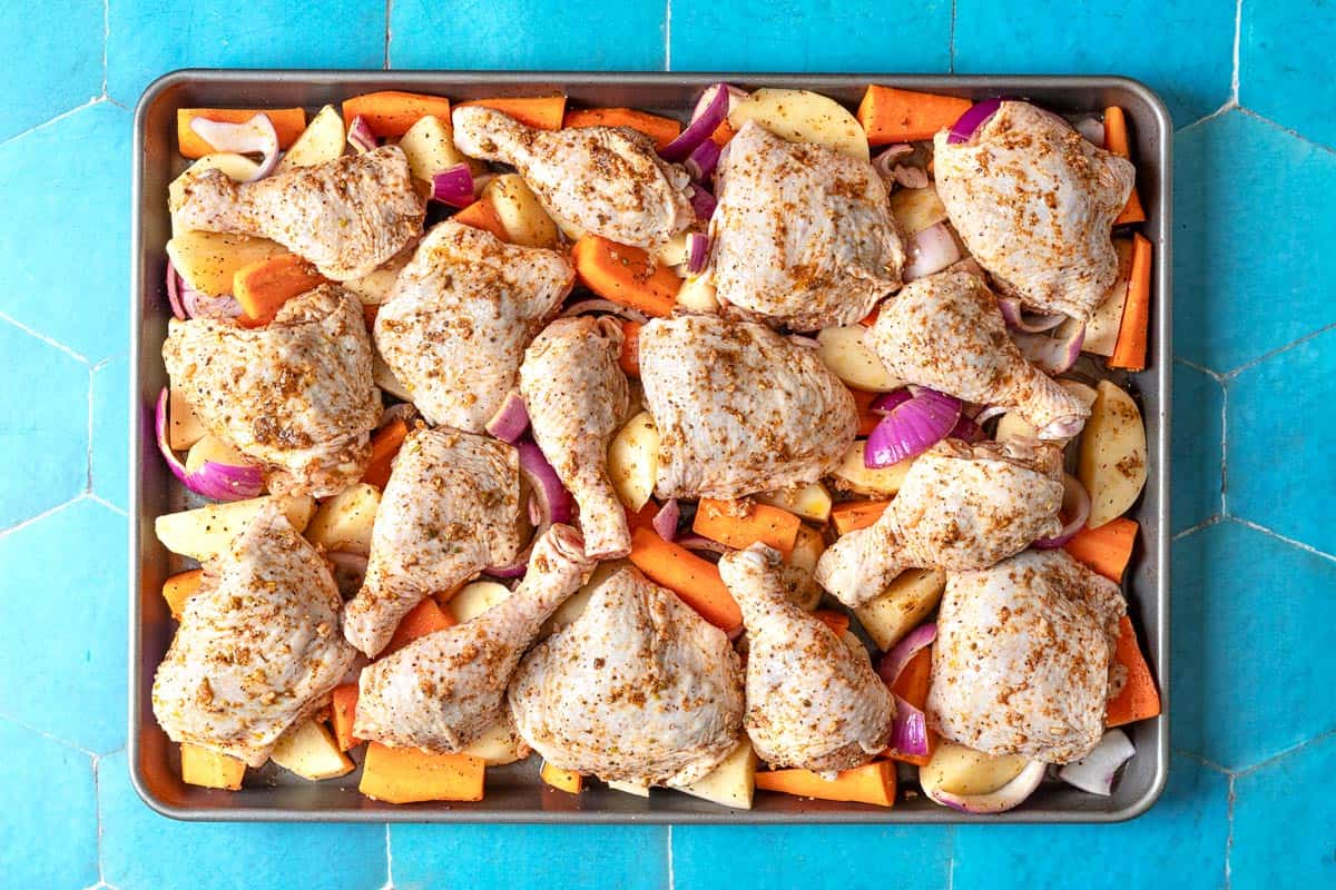 An overhead photo of unbaked sheet pan za'atar chicken with veggies.