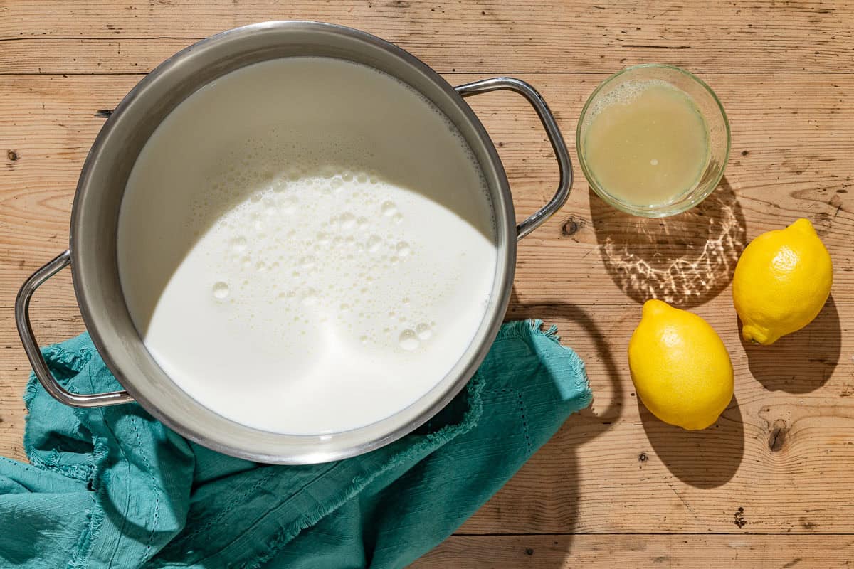 Ingredients for homemade ricotta including milk, lemon juice and lemons.