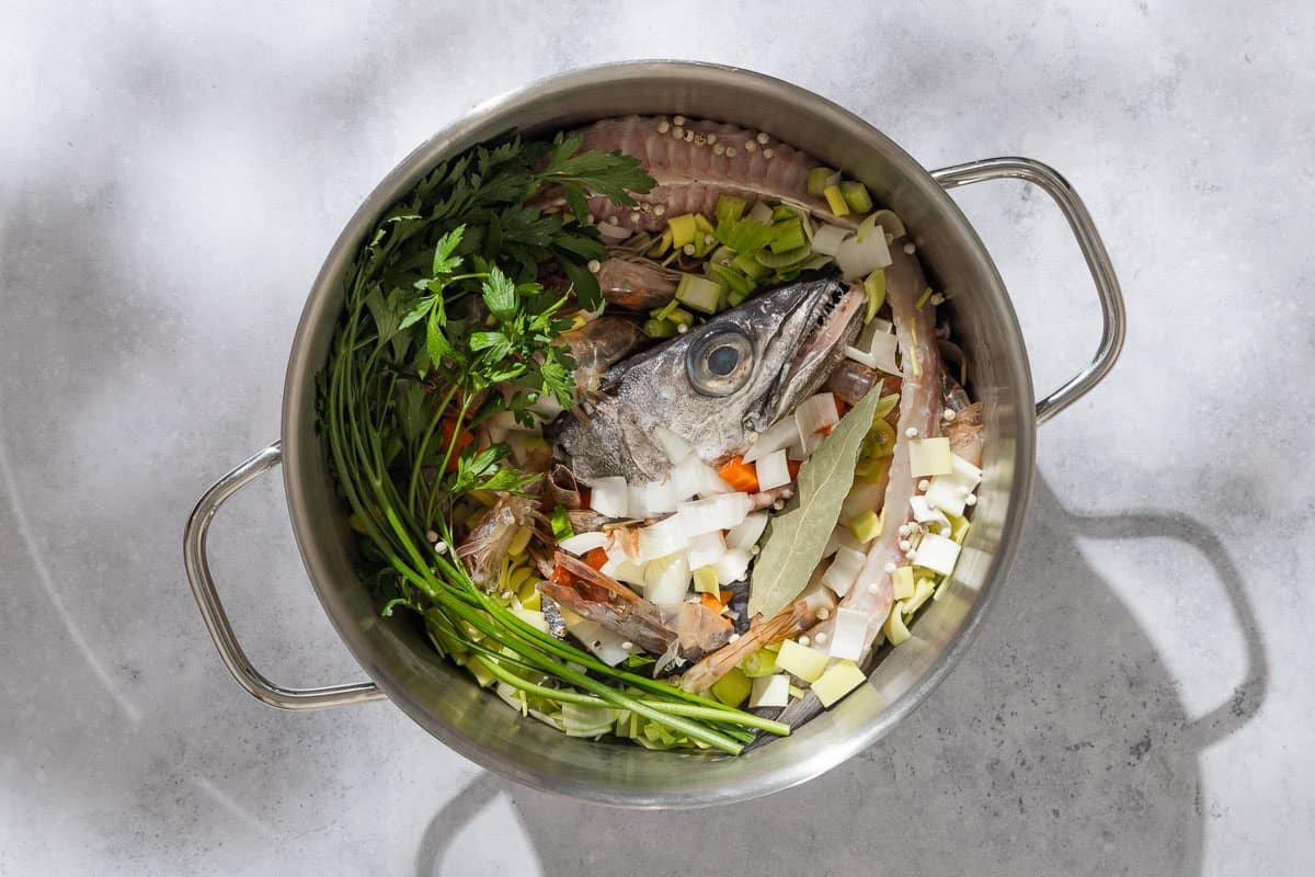 An overhead photo of all of the ingredients for the seafood stock in a large pot.