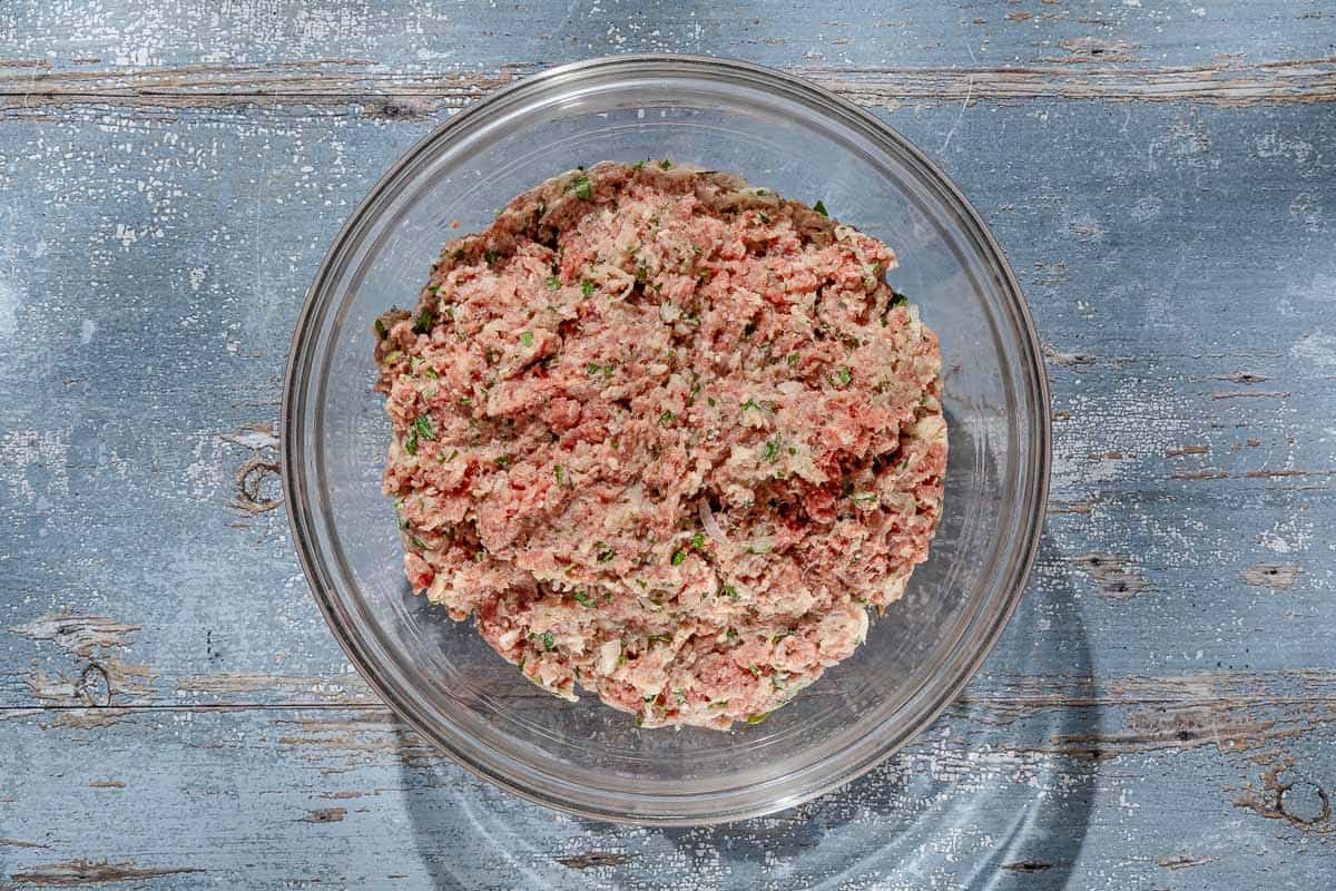 An overhead photo of the meat mixture for the Spanish meatballs in a mixing bowl.