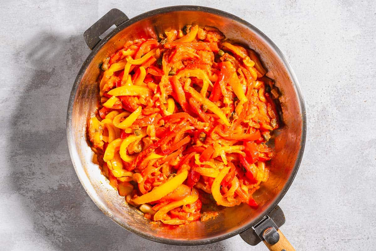 Vegetables for the peperonata being cooked in a skillet.