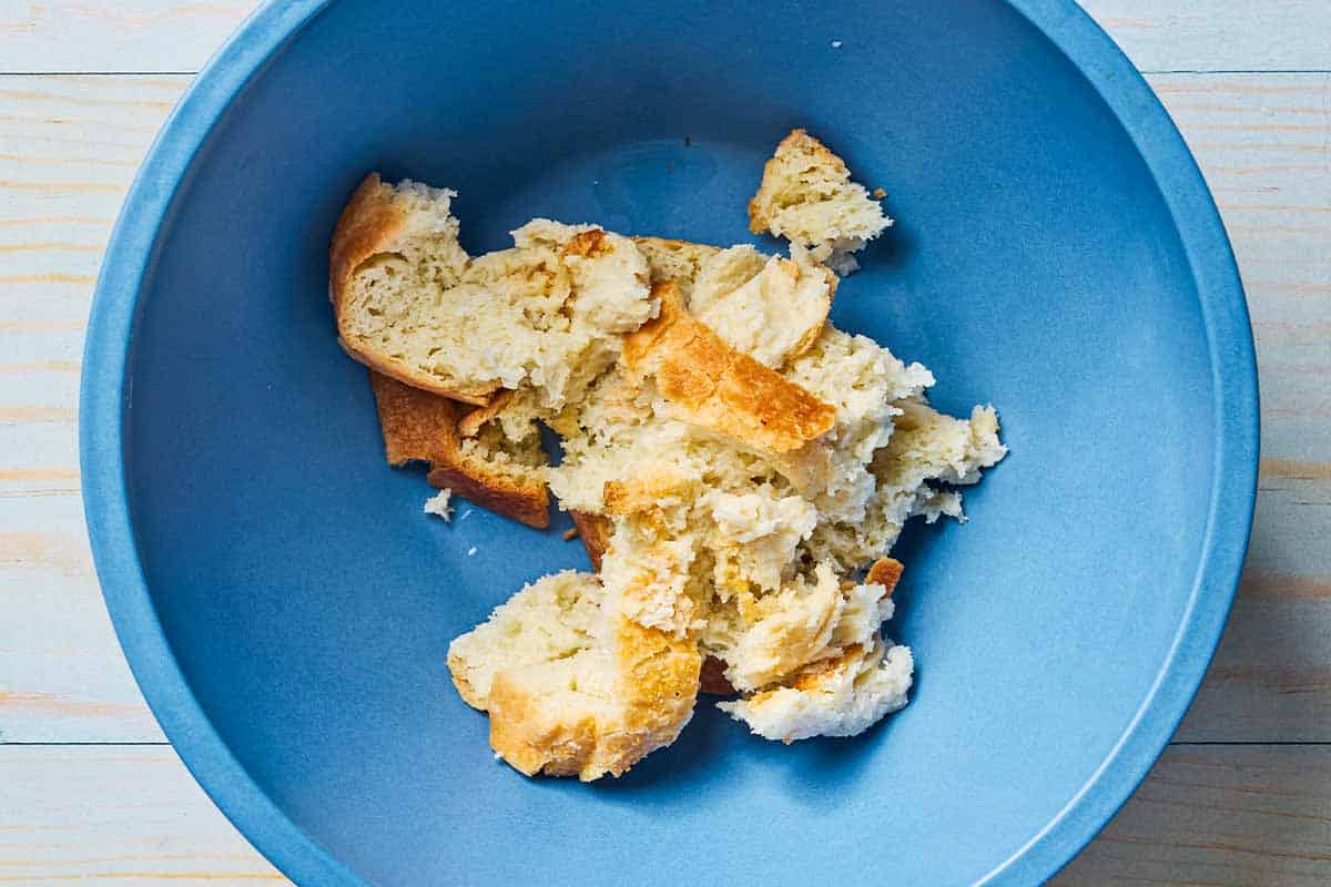 An overhead photo of a torn piece of day old bread in a bowl.