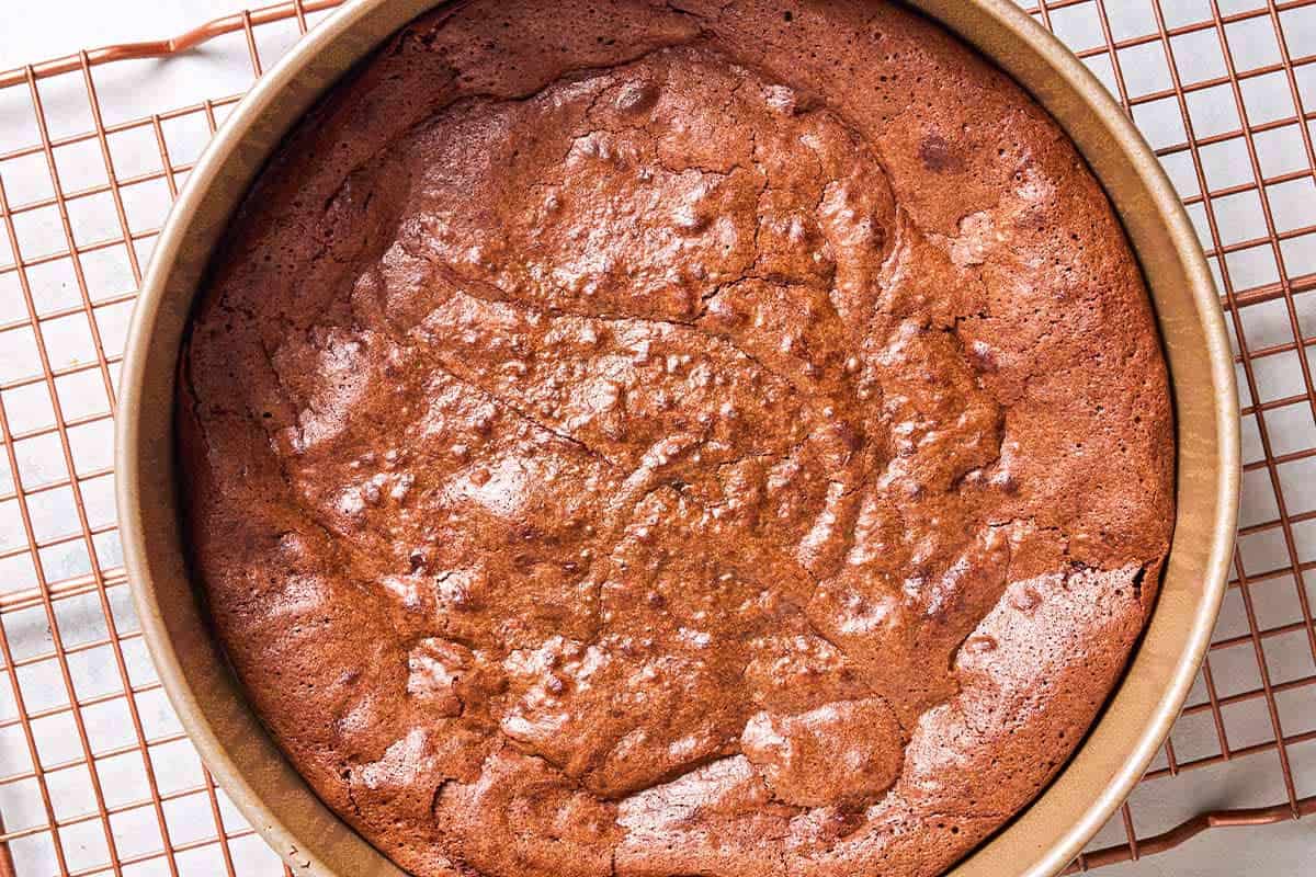 An overhead photo of the flourless chocolate in round baking pan cooling on a wire rack.