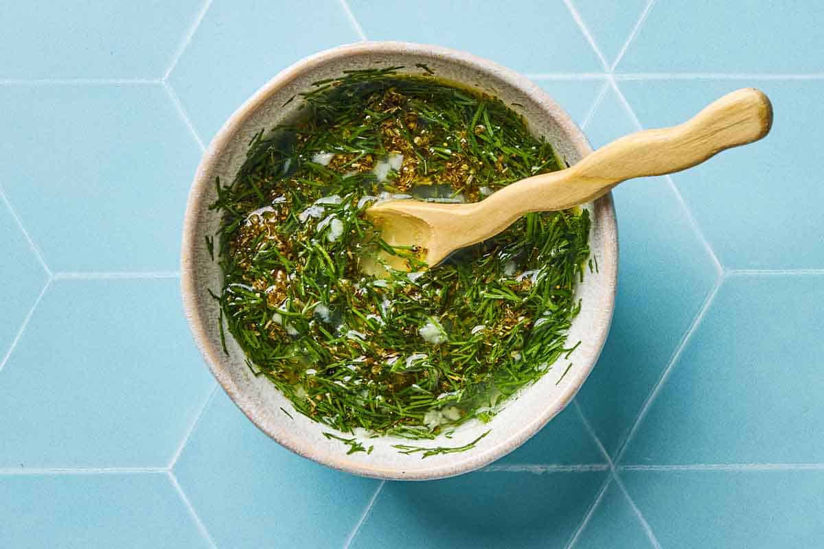 The Greek-style sauce for the Greek salmon in a bowl with a spoon.