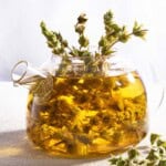 A bunch of Greek mountain tea brewing in water in a glass kettle. Next to this is a spring of the tea bunch.