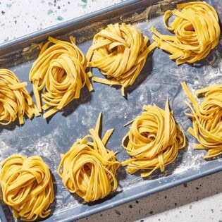 An overhead photo of uncooked homemade pasta noodles formed into 8 nest shapes.