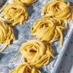 A close up photo of uncooked homemade pasta noodles formed into several nest shapes.