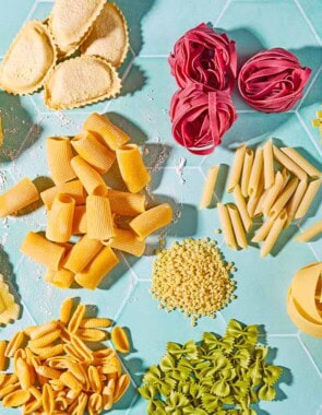 An overhead photo a a variety of uncooked pasta shapes.