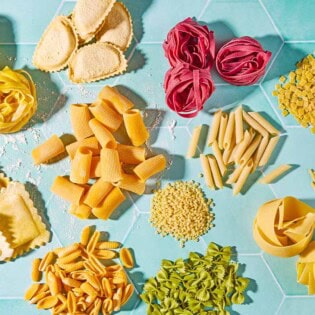 An overhead photo a a variety of uncooked pasta shapes.