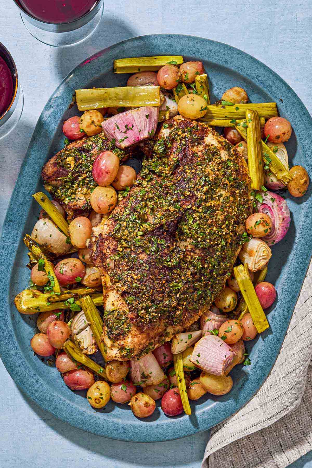 An overhead photo of roast turkey breast with grapes and vegetables on a serving platter.