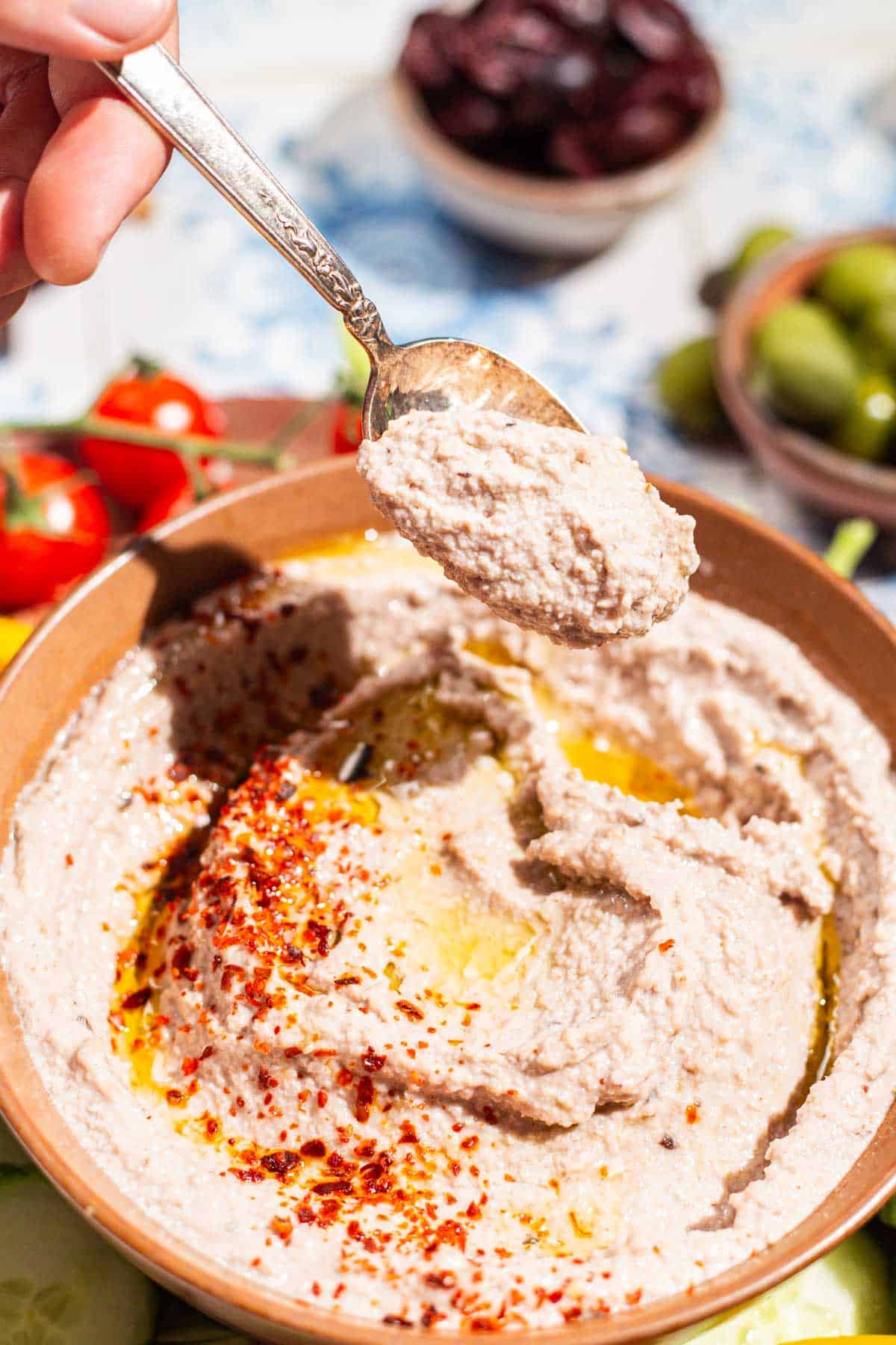 A close up of some tarator sauce on a spoon being held above the rest of the tarator sauce in a bowl.