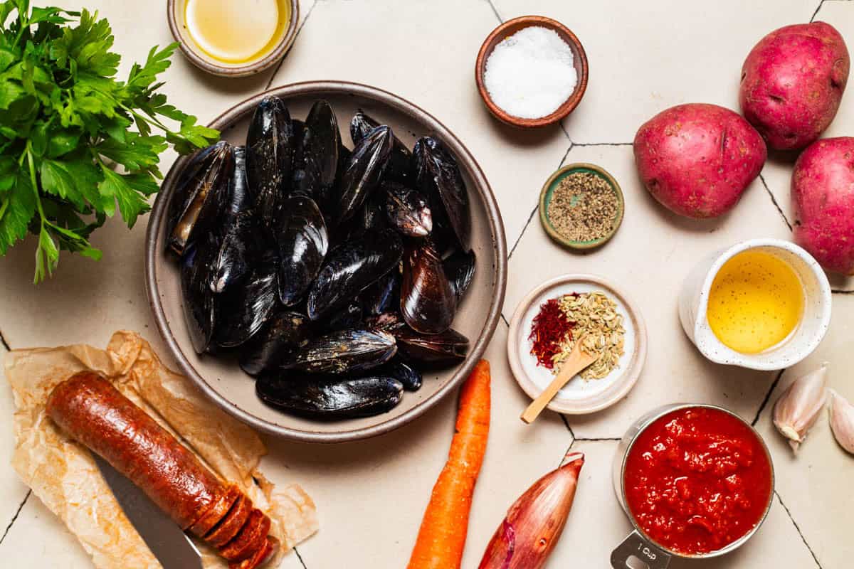 Ingredients for mussels with chorizo including mussels, chorizo, crushed tomatoes, olive oil, shallots, carrot, garlic, fennel, saffron, white wine, red baby potatoes, salt, black pepper and parsley.