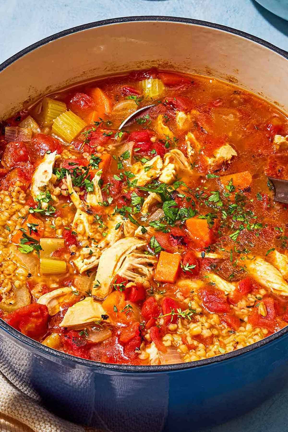 A close up of freekeh soup with chicken in a large pot.