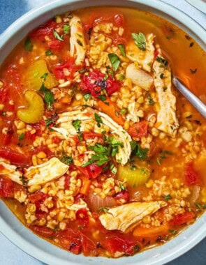 An overhead photo of freekeh soup with chicken in a bowl with a spoon.