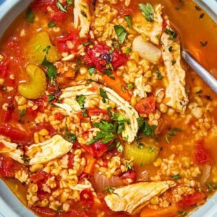 An overhead photo of freekeh soup with chicken in a bowl with a spoon.