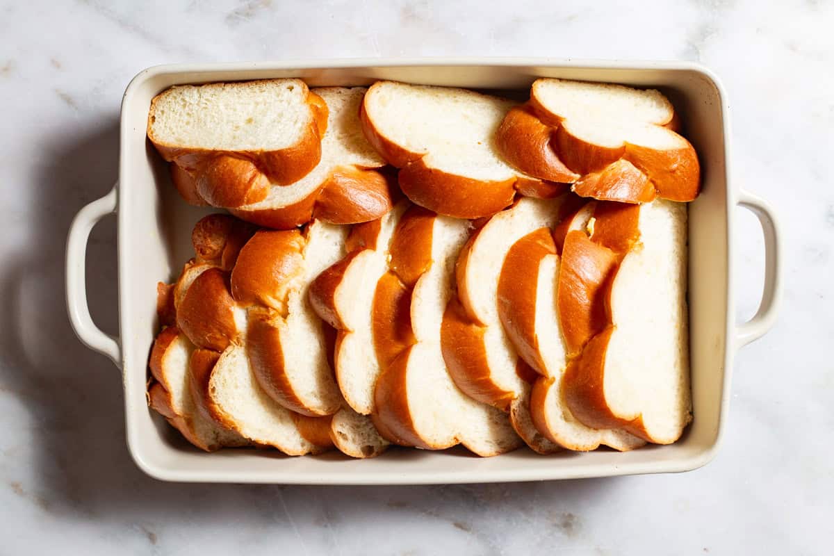 An overhead photo of slices of challah arranged in a baking dish.